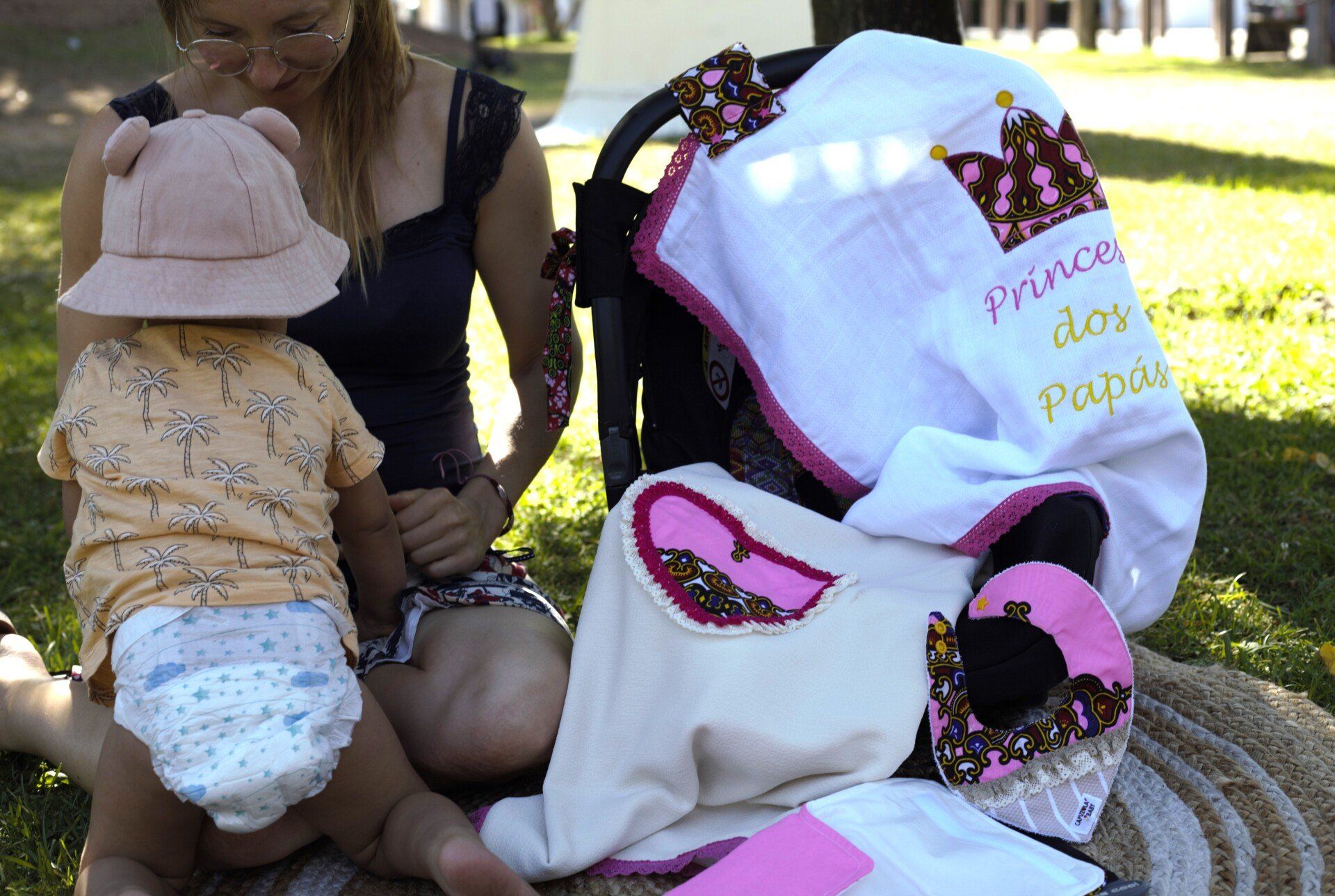 Uma mulher está ajoelhada ao lado de um bebê e um cobertor que diz príncipe nele