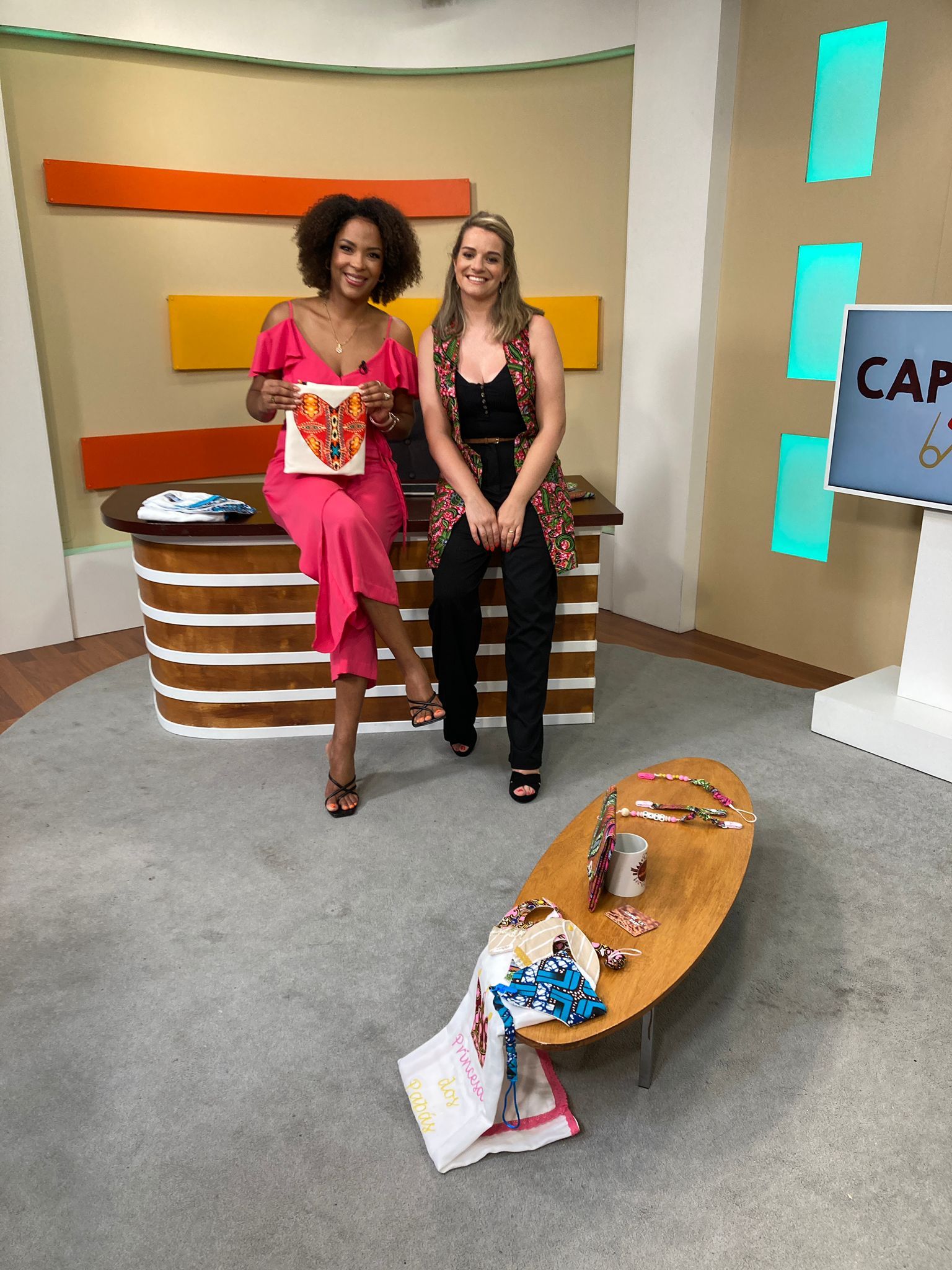 Duas mulheres estão sentadas em uma mesa de estúdio.