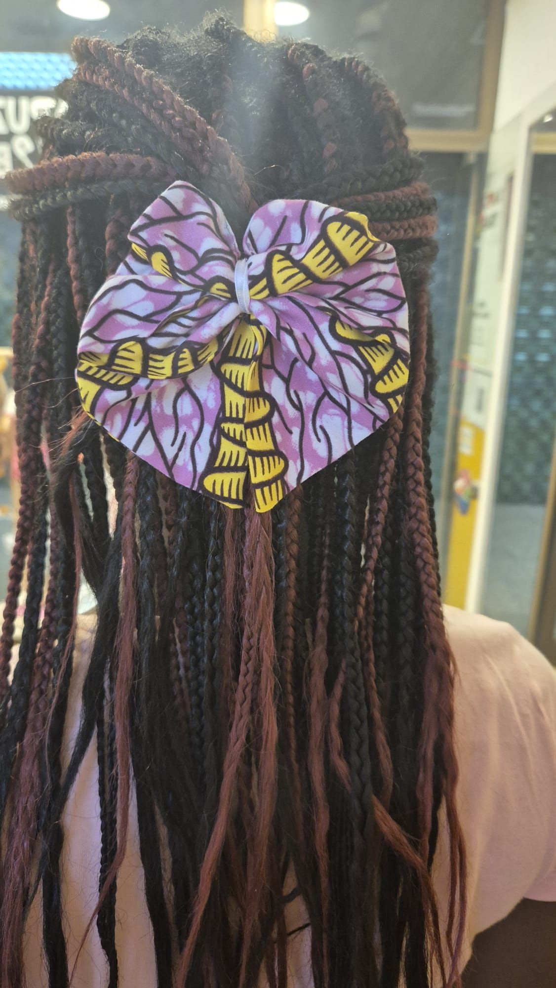 Uma mulher com dreadlocks está usando um laço roxo no cabelo.