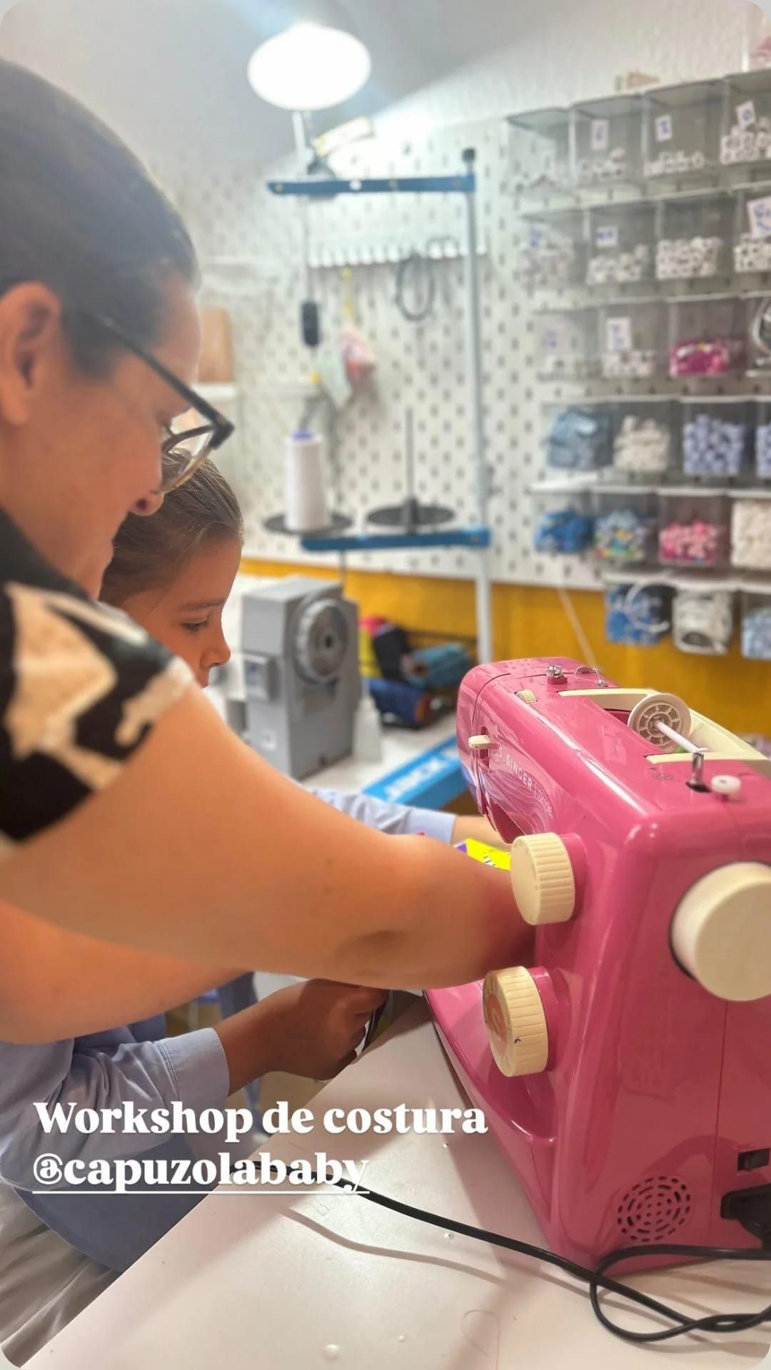 Uma mulher está ensinando uma criança a usar uma máquina de costura rosa.