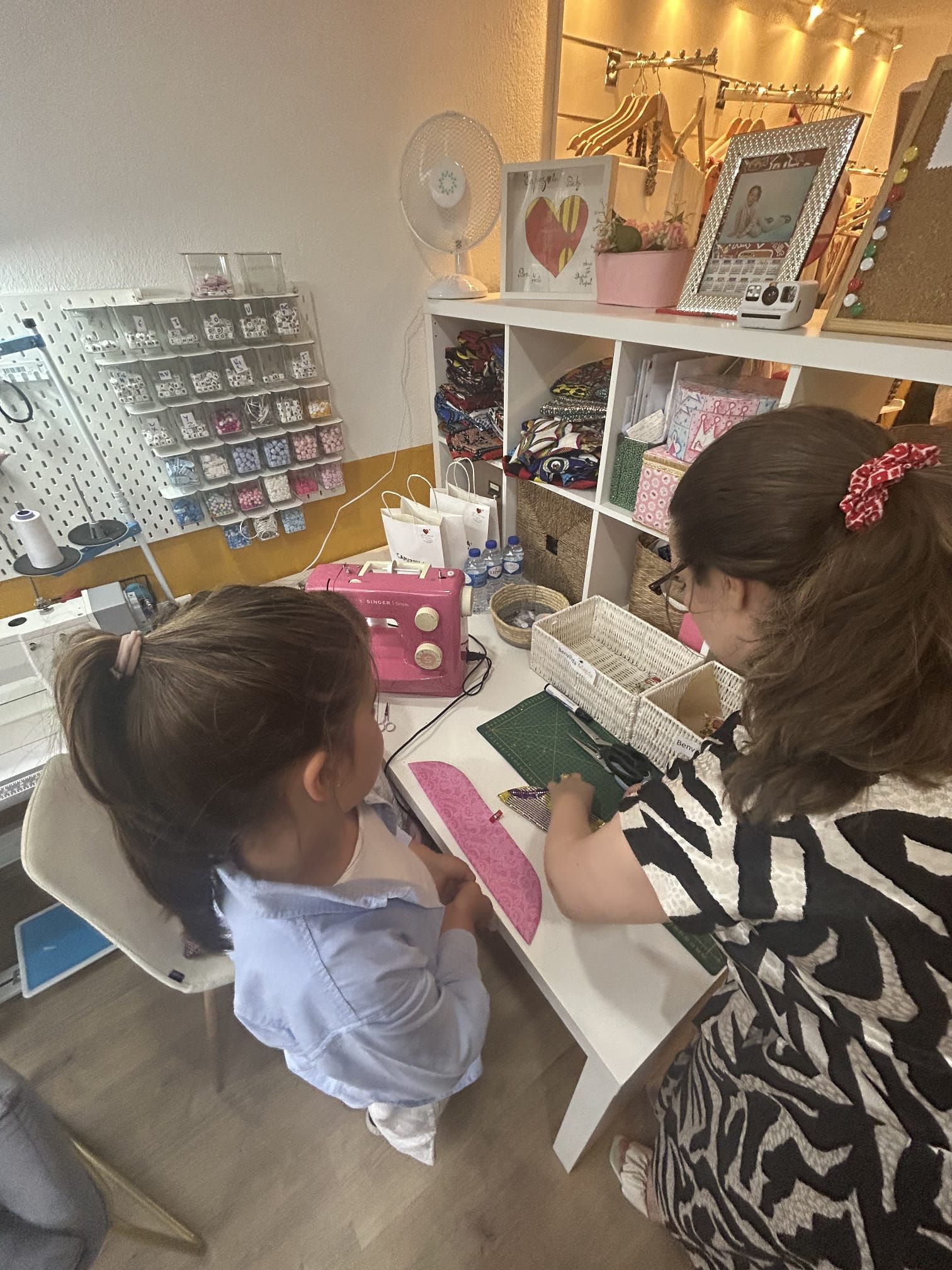 Duas meninas estão sentadas à mesa com uma máquina de costura.