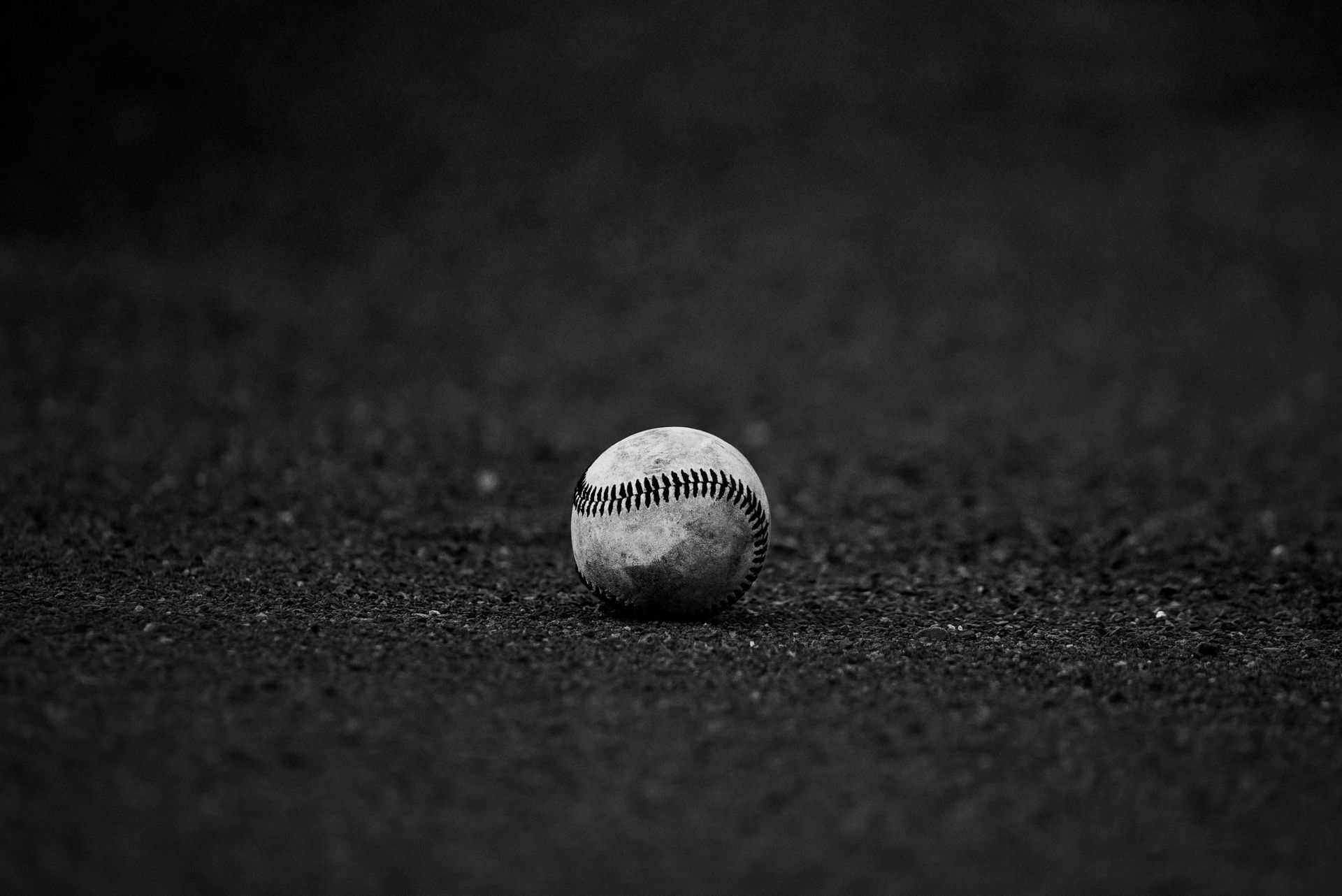 Uma bola de beisebol está no chão em uma foto em preto e branco.