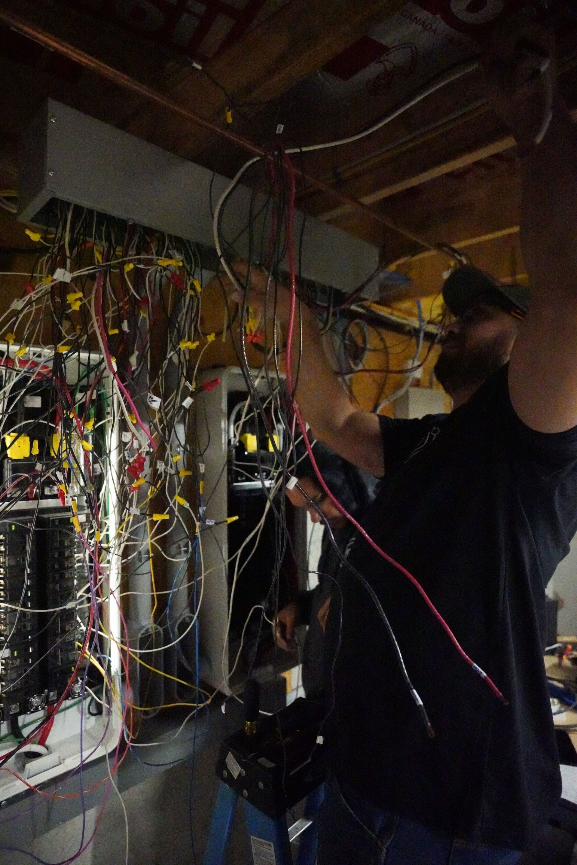 a man is working on a bunch of wires in a room .