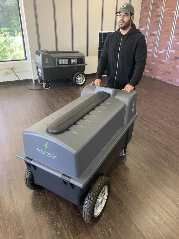 a man is standing next to a large gray box with wheels .