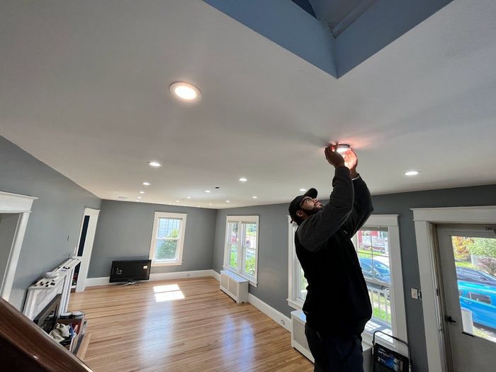 A man is fixing a light in a living room.