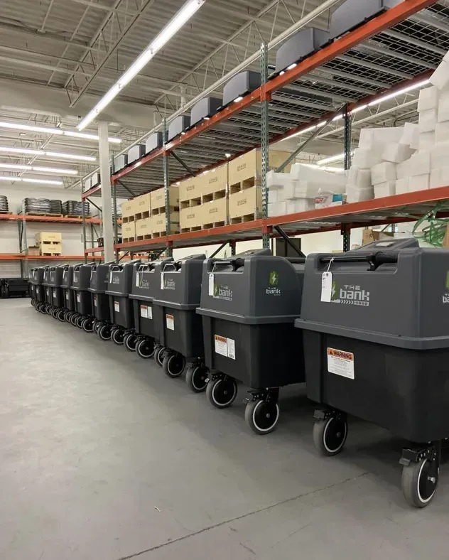 a row of trash cans are lined up in a warehouse .