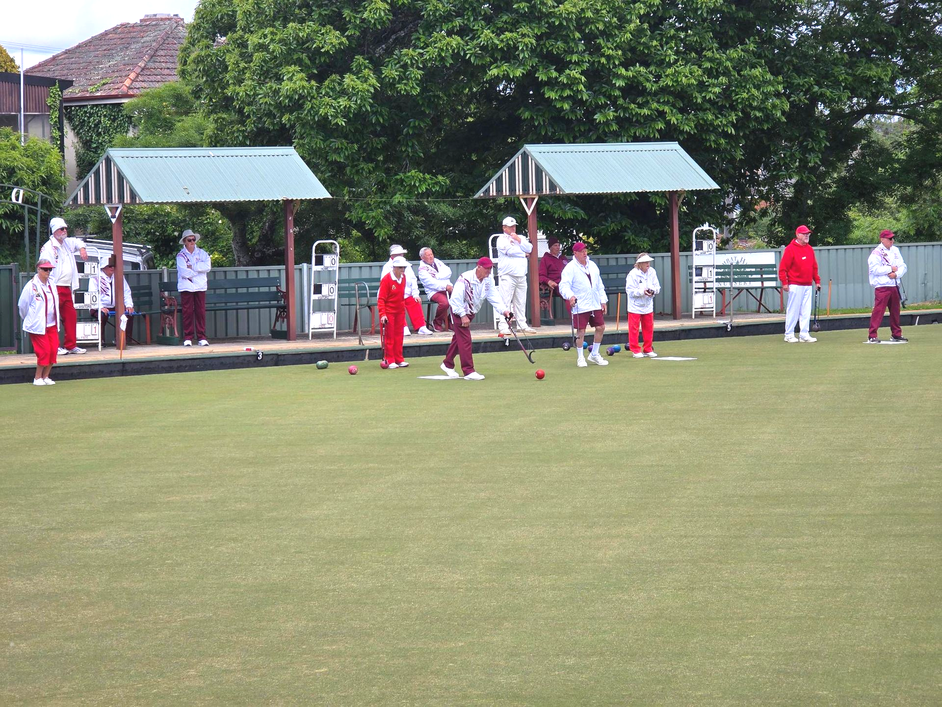 Pennant Bowlers in red, white and maroon uniform on green grass.