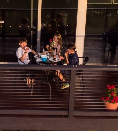 Three children sitting at a restaurant table on balcony.