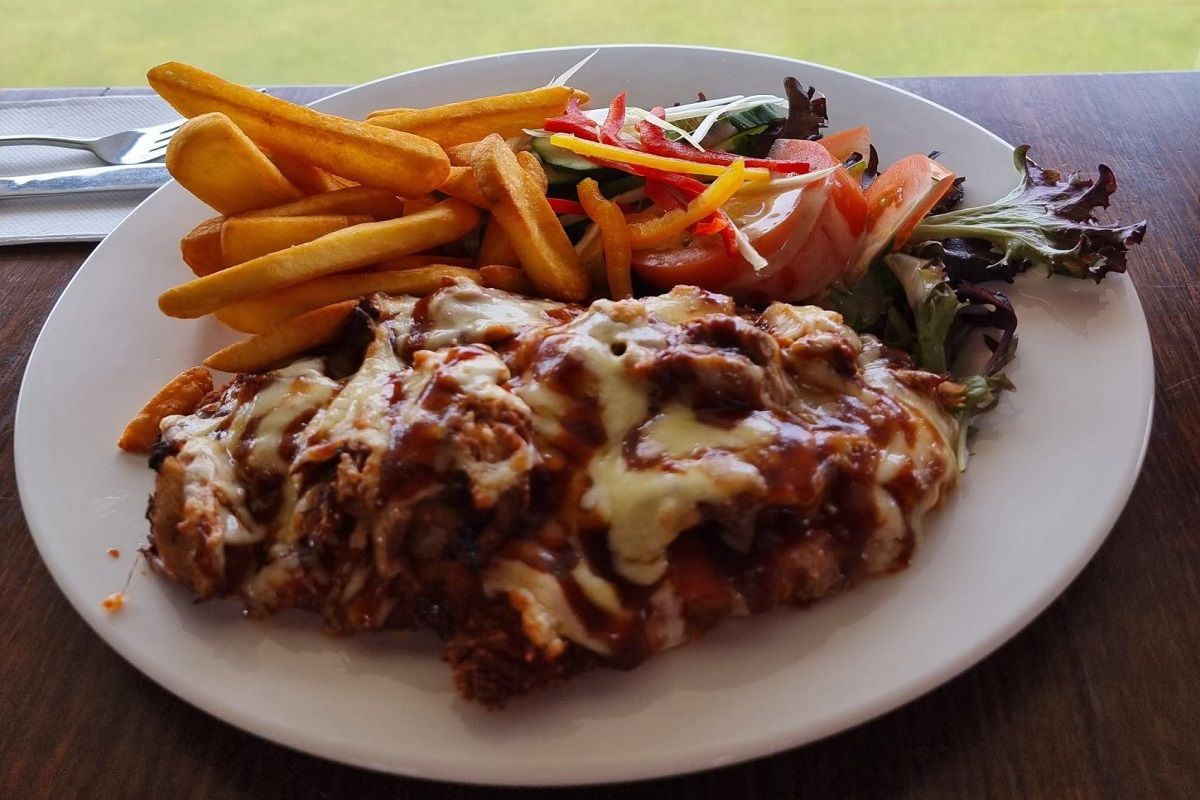 Plate of chicken parma with fried chips and salad.