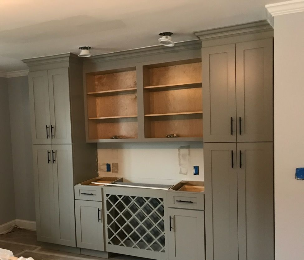 Built-in gray cabinets and open shelves in a recessed wall niche with a wine rack below.