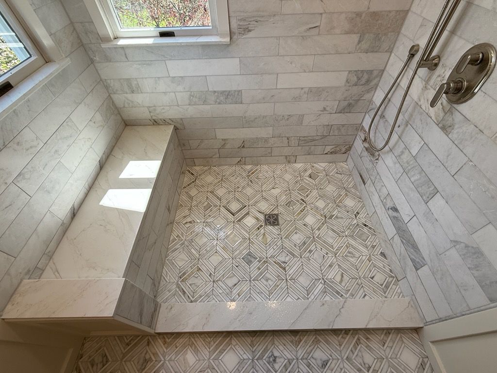 Modern tiled shower with bench and patterned floor, viewed from above