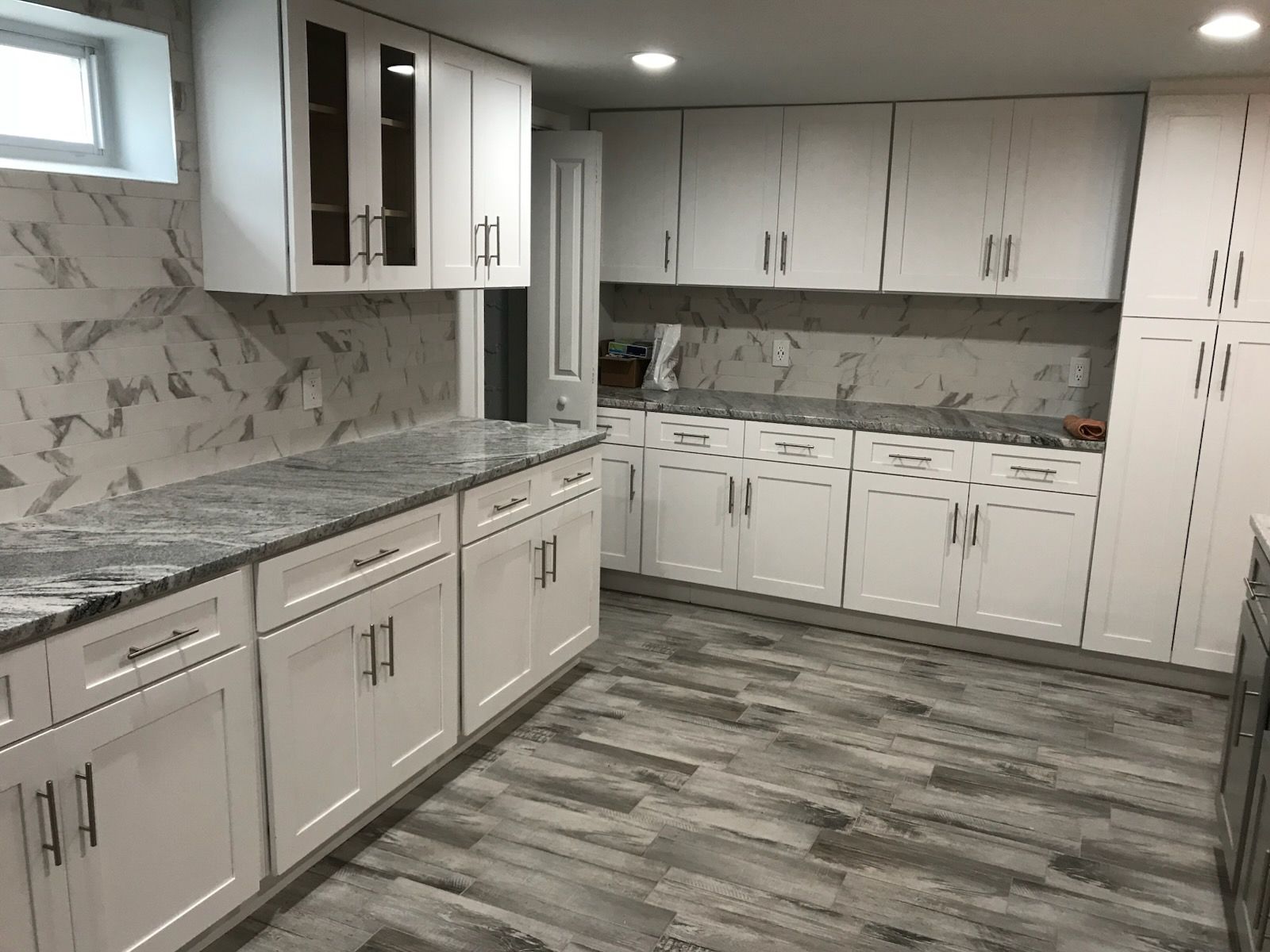 Modern kitchen with white cabinets, gray countertops, and gray wood-look flooring