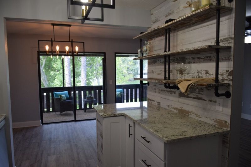 Modern kitchen with white cabinets, marble island, open shelving, and sliding glass doors to a balcony