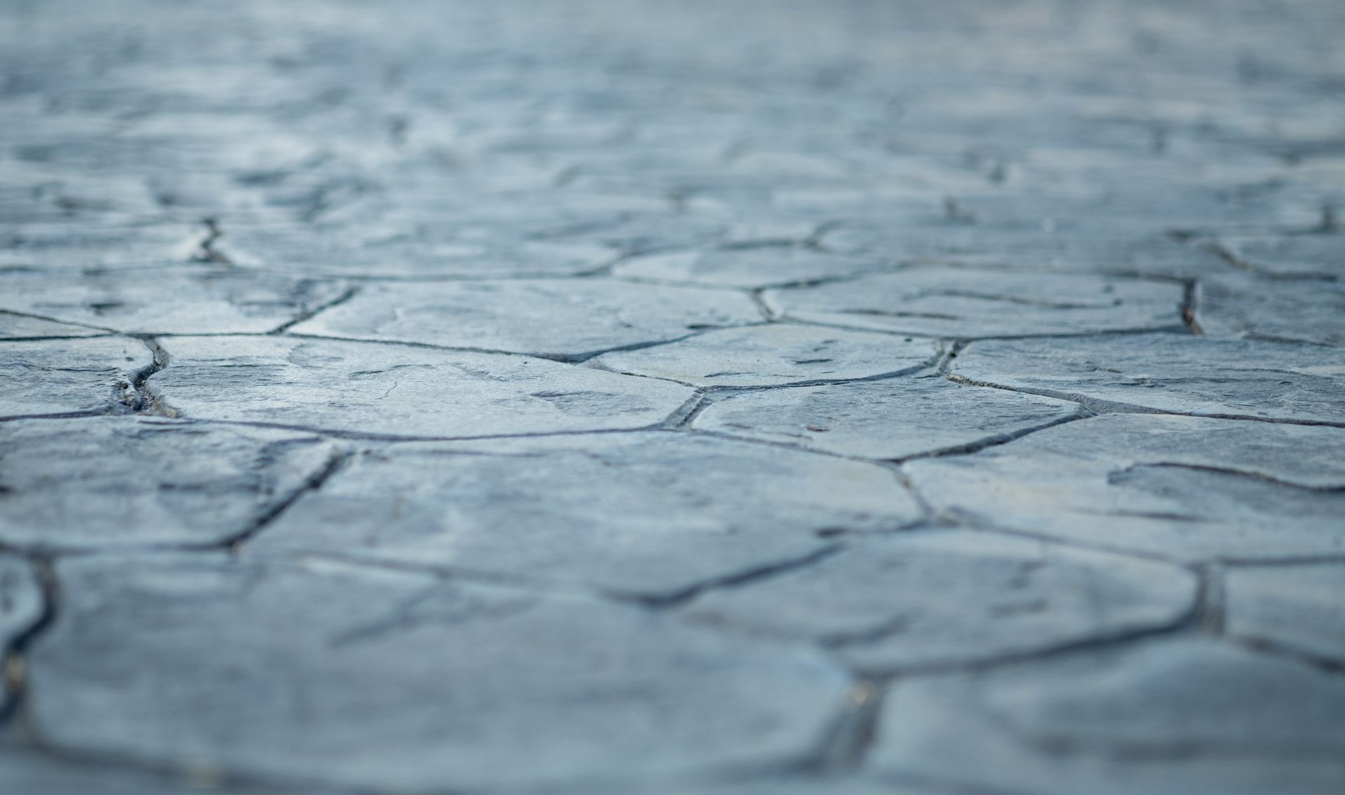 Textured stamped concrete surface with irregular stone pattern in soft focus across the frame.