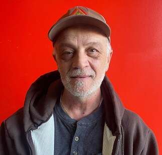 A man with a beard is wearing a hat and a hoodie.