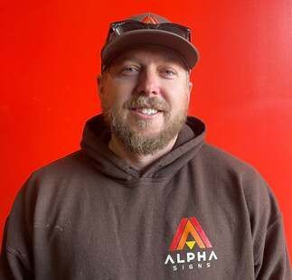 A man with a beard is wearing a hat and sunglasses and a hoodie.