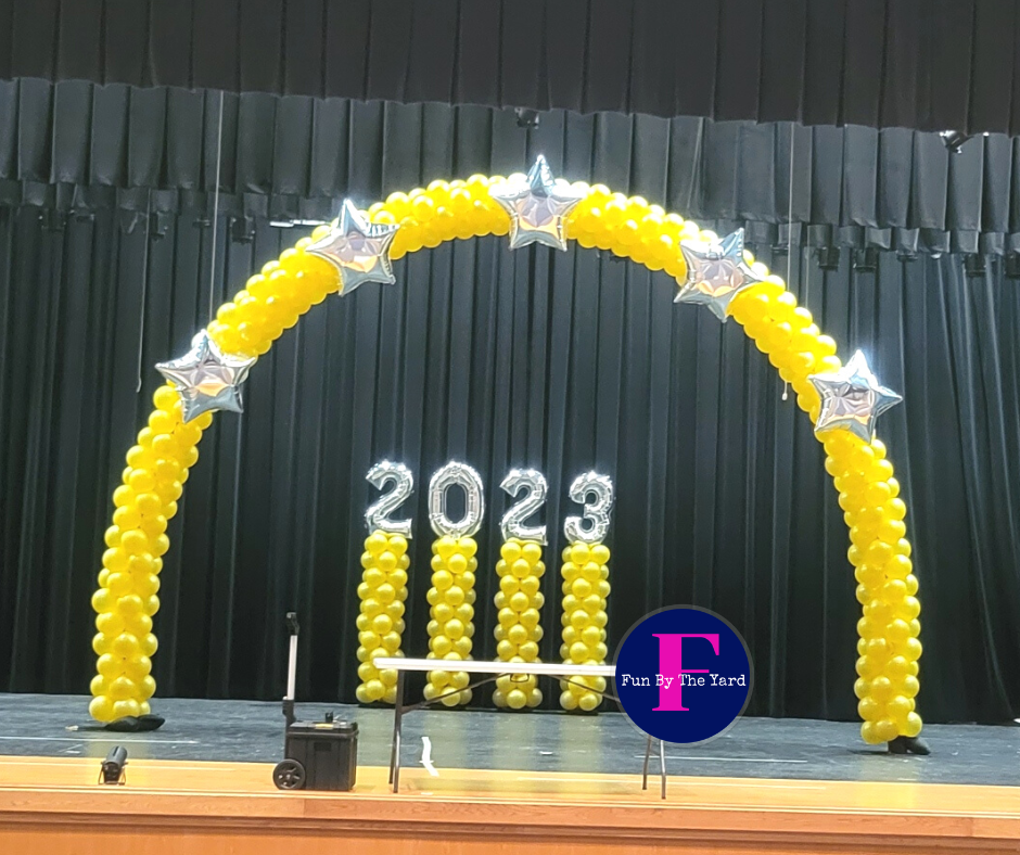 A yellow balloon arch with the year 2023 on it