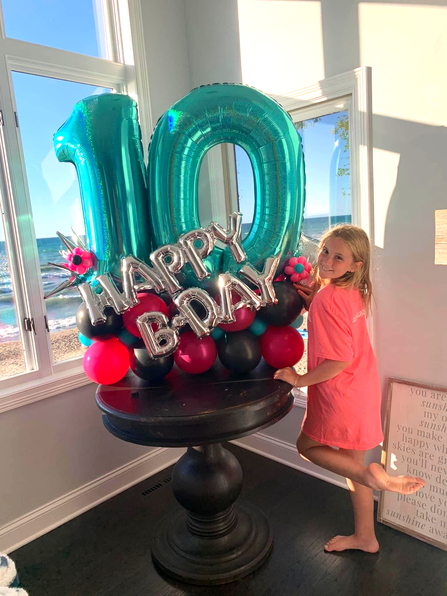 Girl poses next to a balloon arrangement with the number 10, balloons say 
