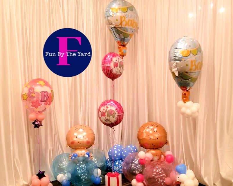 A bunch of balloons are sitting on a table in front of a white curtain.