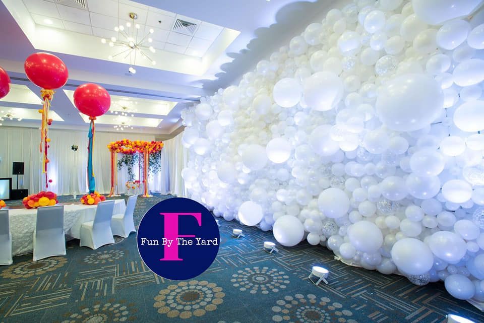 A large room filled with a white balloon wall for a wedding
