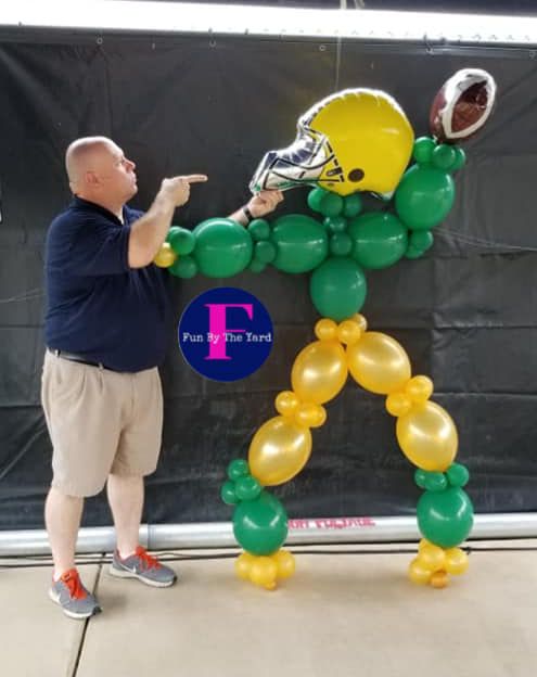 A man is pointing at a football player made out of balloons