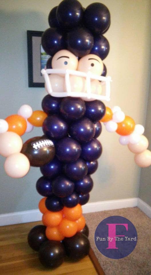 A balloon sculpture of a football player wearing a helmet and holding a football.