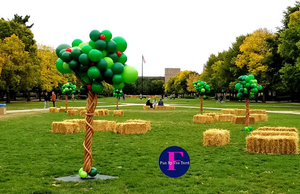a tree made out of green balloons in a park
