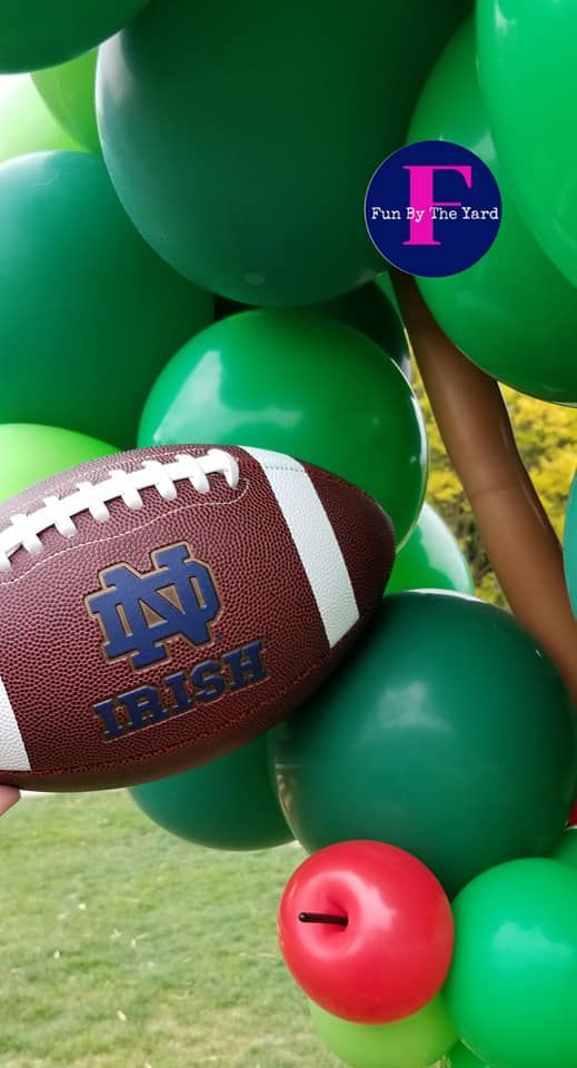 A football is sitting on top of a bunch of green balloons.