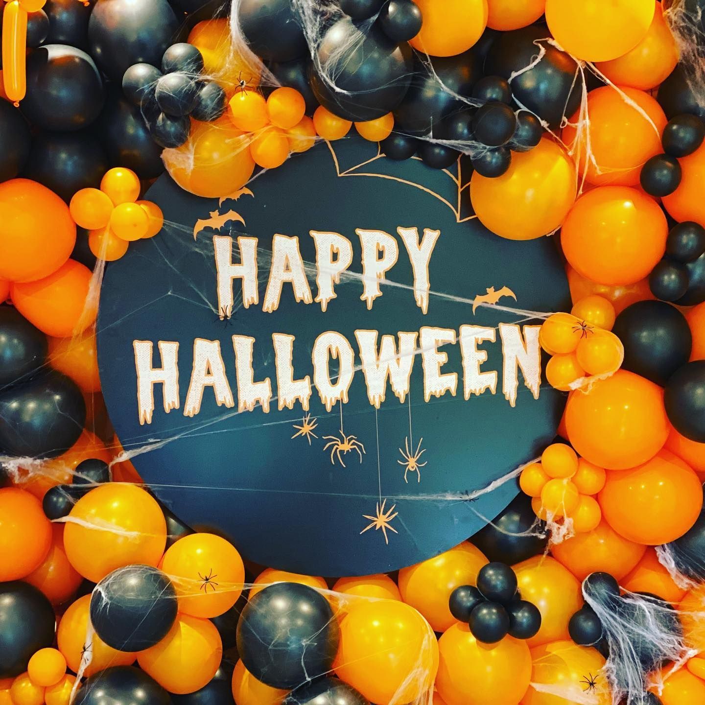 A sign that says happy halloween is surrounded by orange and black balloons