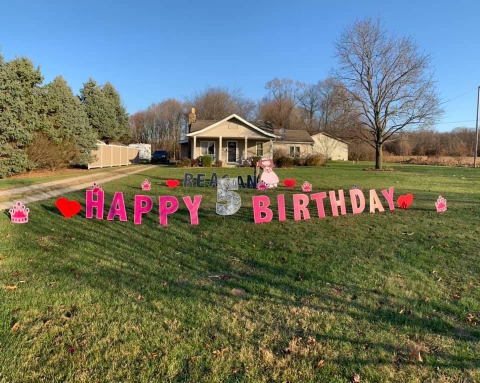 A happy 5th birthday sign is in the grass in front of a house.