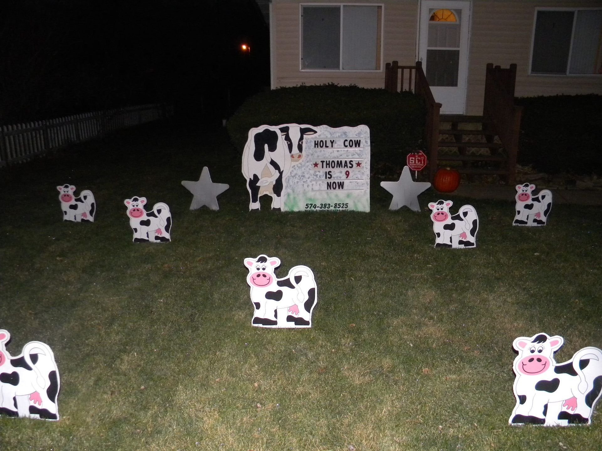 A lawn decorated with cows and a sign that says