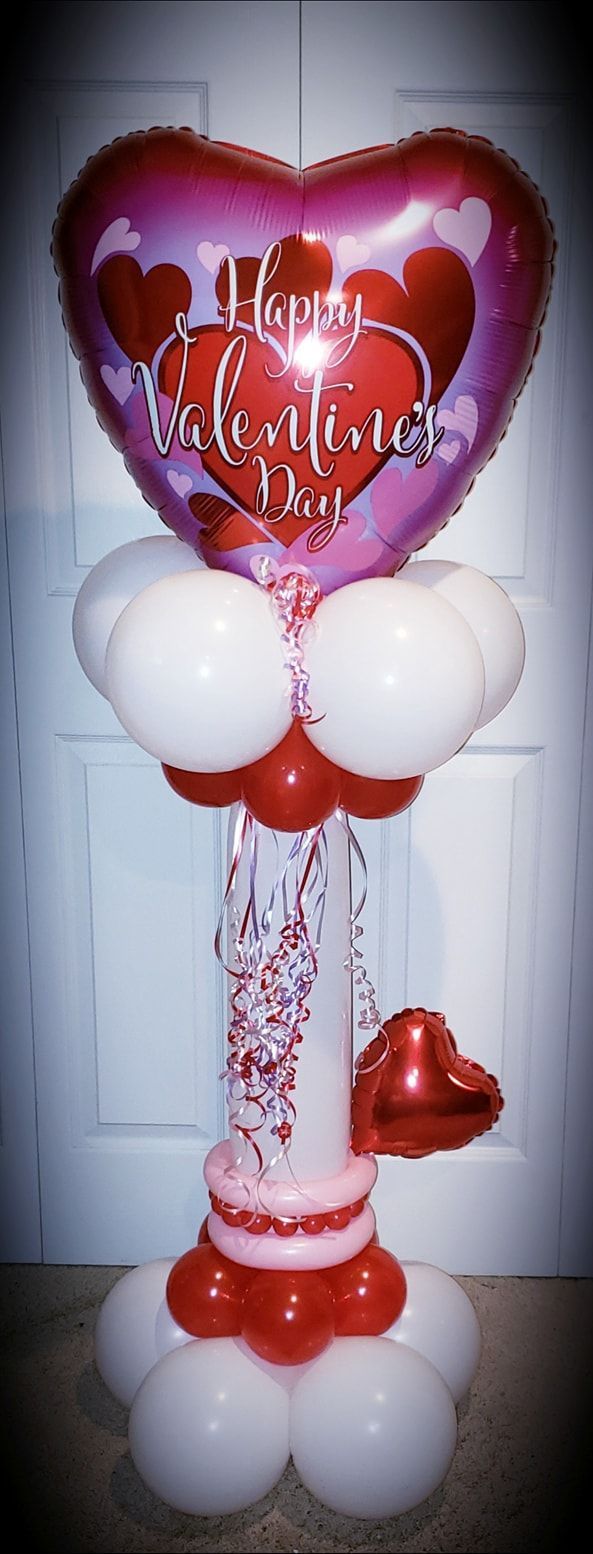 A heart shaped balloon is sitting on top of a bunch of balloons.