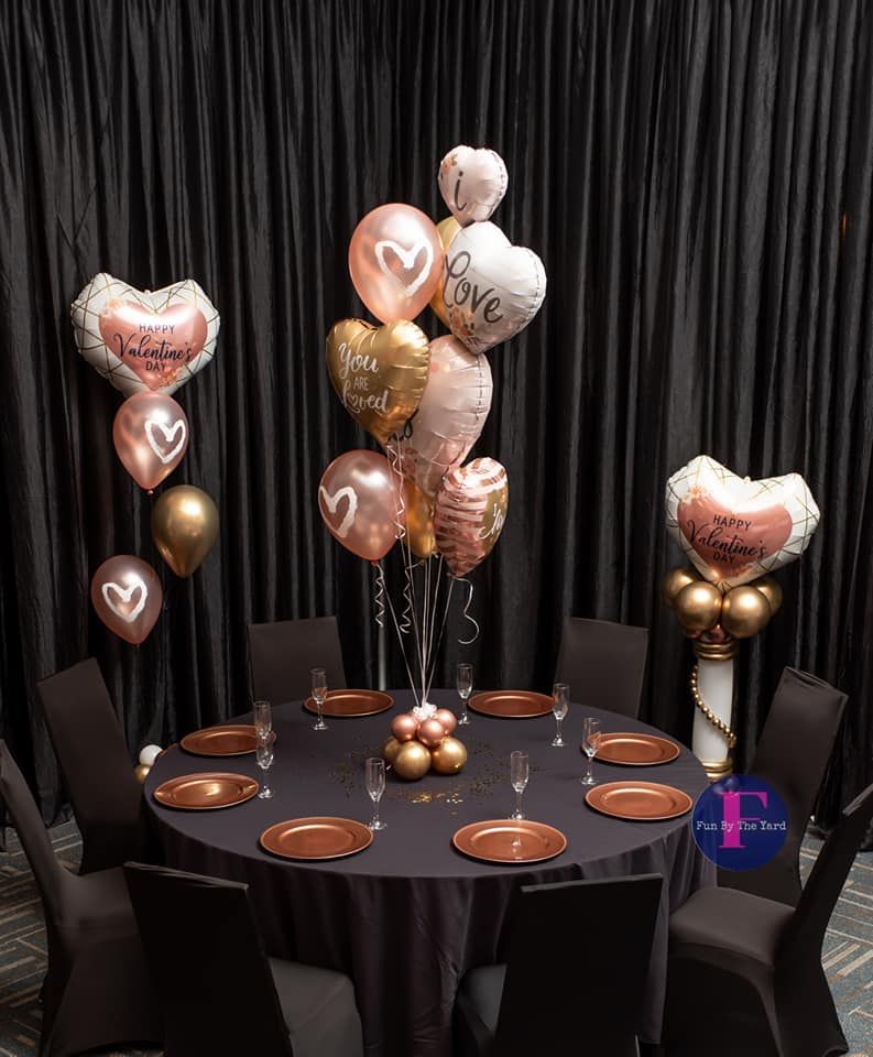 A table with plates , glasses , and balloons on it.