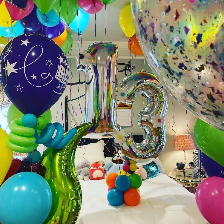 A bedroom decorated with balloons and a number 13.  Party Bomb