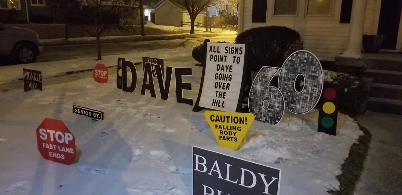 A sign that says dave and baldy is in the snow in front of a house.