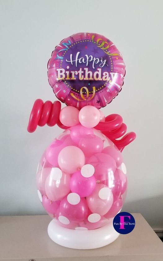 A pink balloon with a happy birthday balloon on top of it