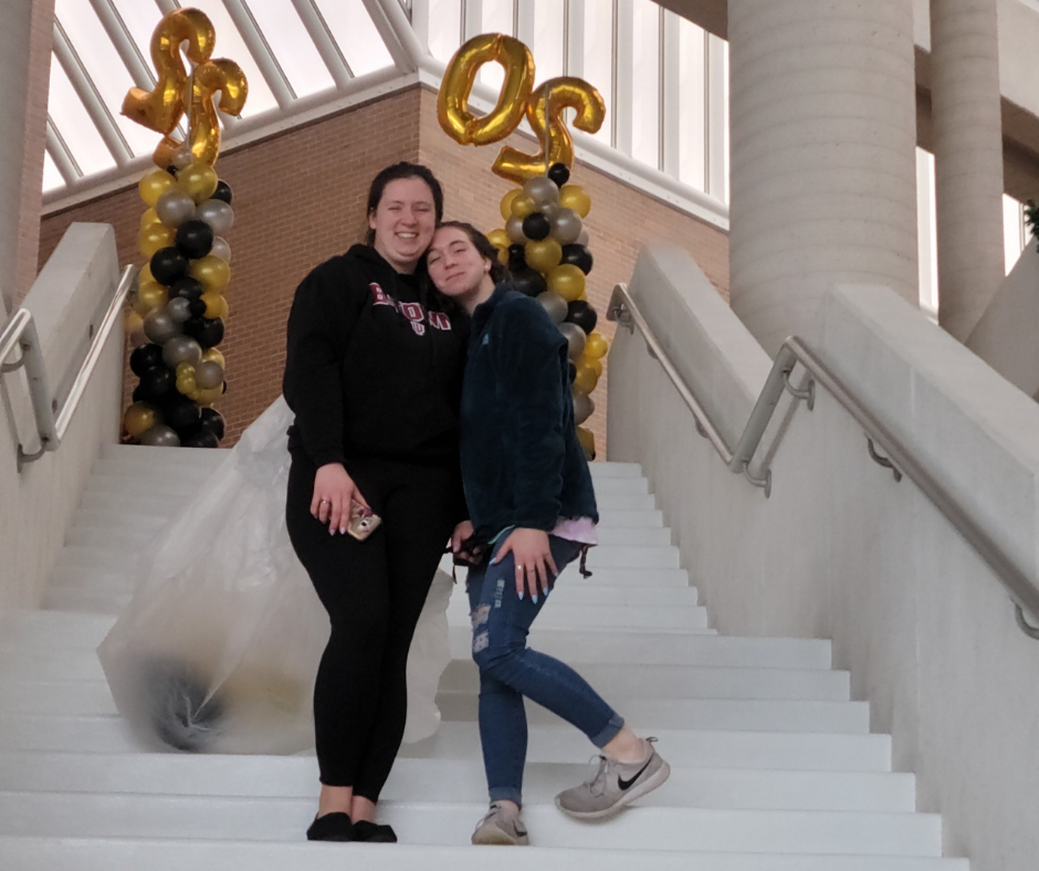 Two women are posing for a picture on a set of stairs