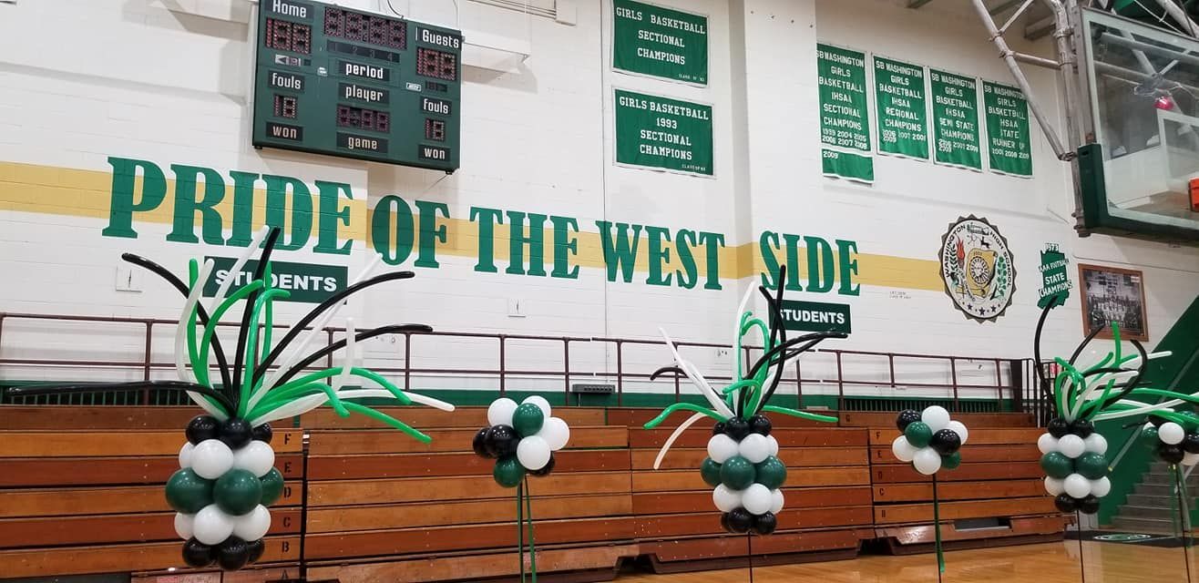 A basketball court decorated with balloons and a sign that says pride of the west side