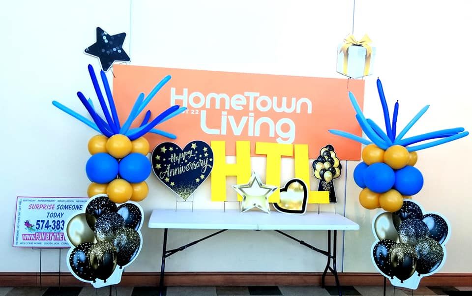A table with balloons and a sign that says hometown living