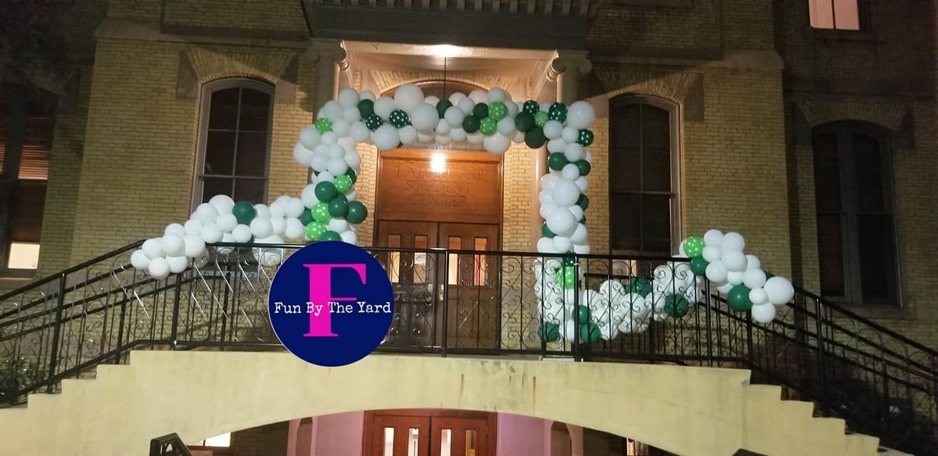 a building with a balcony and stairs decorated with green and white balloons