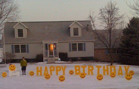 A house with a happy birthday sign in front of it. Smile themed yard card.