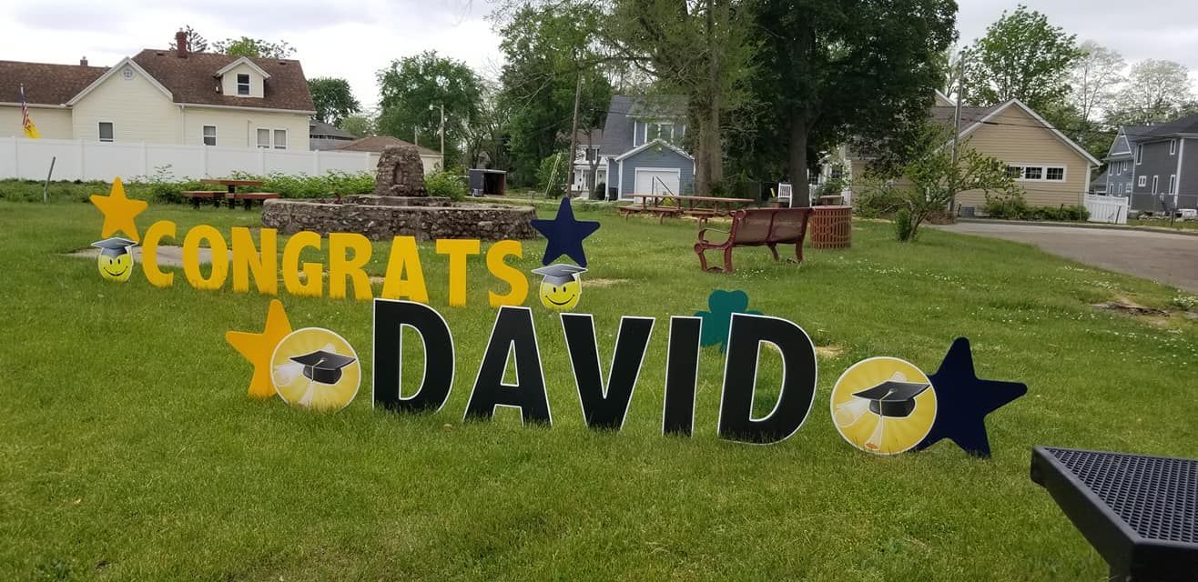 A congratulations sign for david is sitting in the grass.