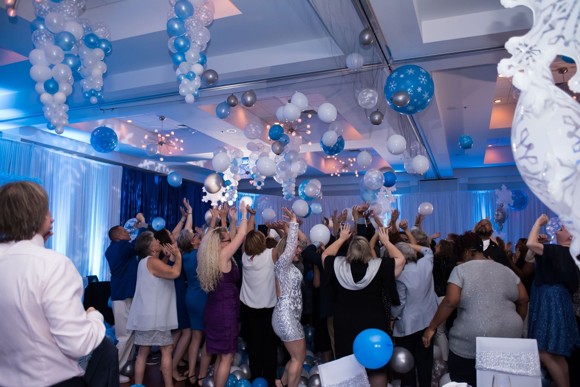 A large group of people are dancing in a room with balloons hanging from the ceiling.  Balloon Dorp