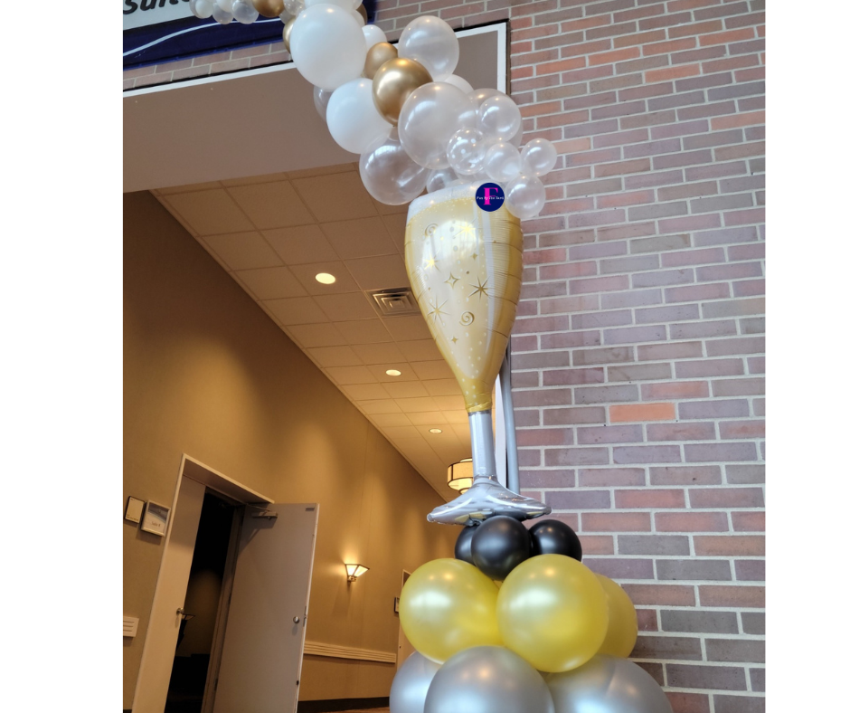 A champagne glass made out of balloons in front of a brick wall.