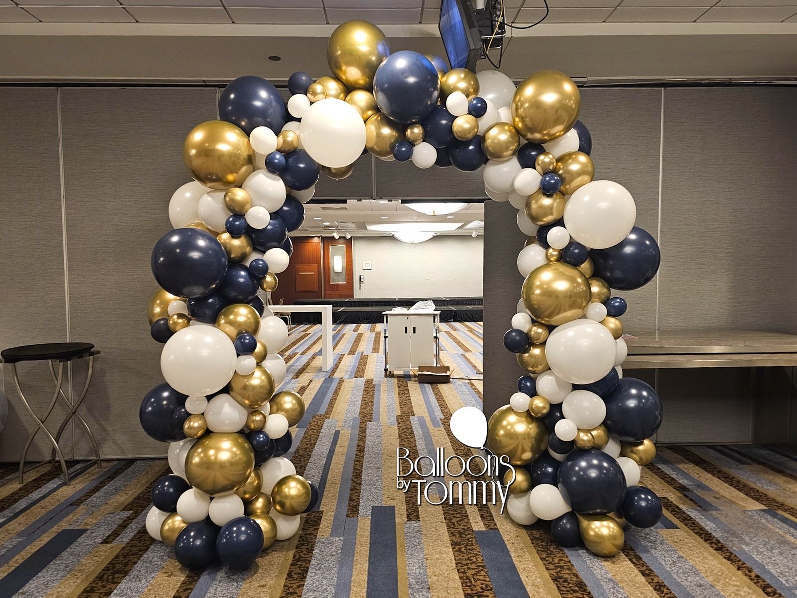 There is a large arch made of balloons in a room.