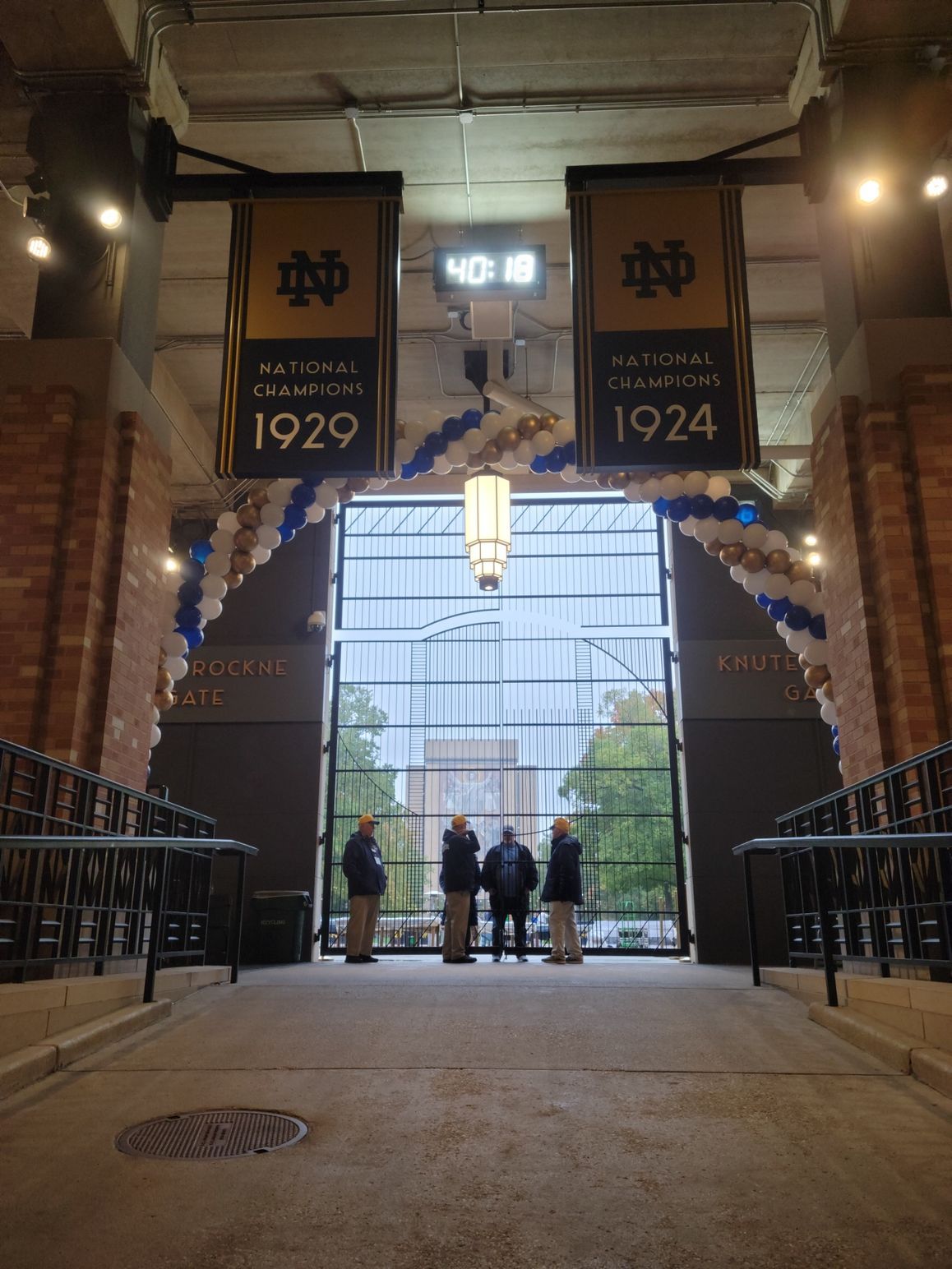 A group of people standing in front of a sign that says 1924.  balloon arch