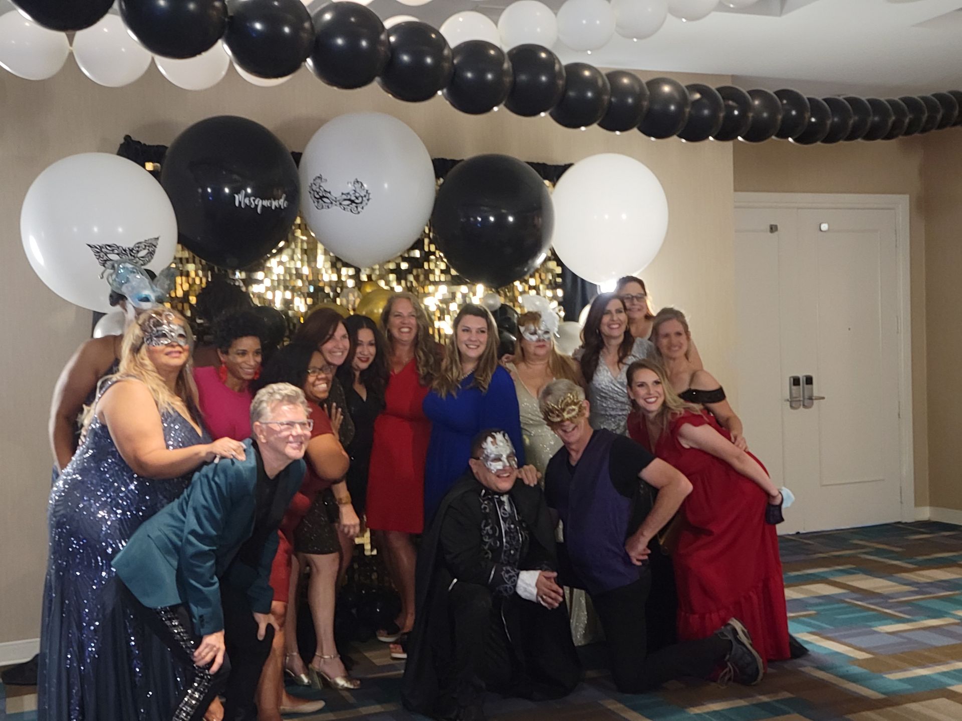 A group of people posing for a picture with balloons hanging from the ceiling