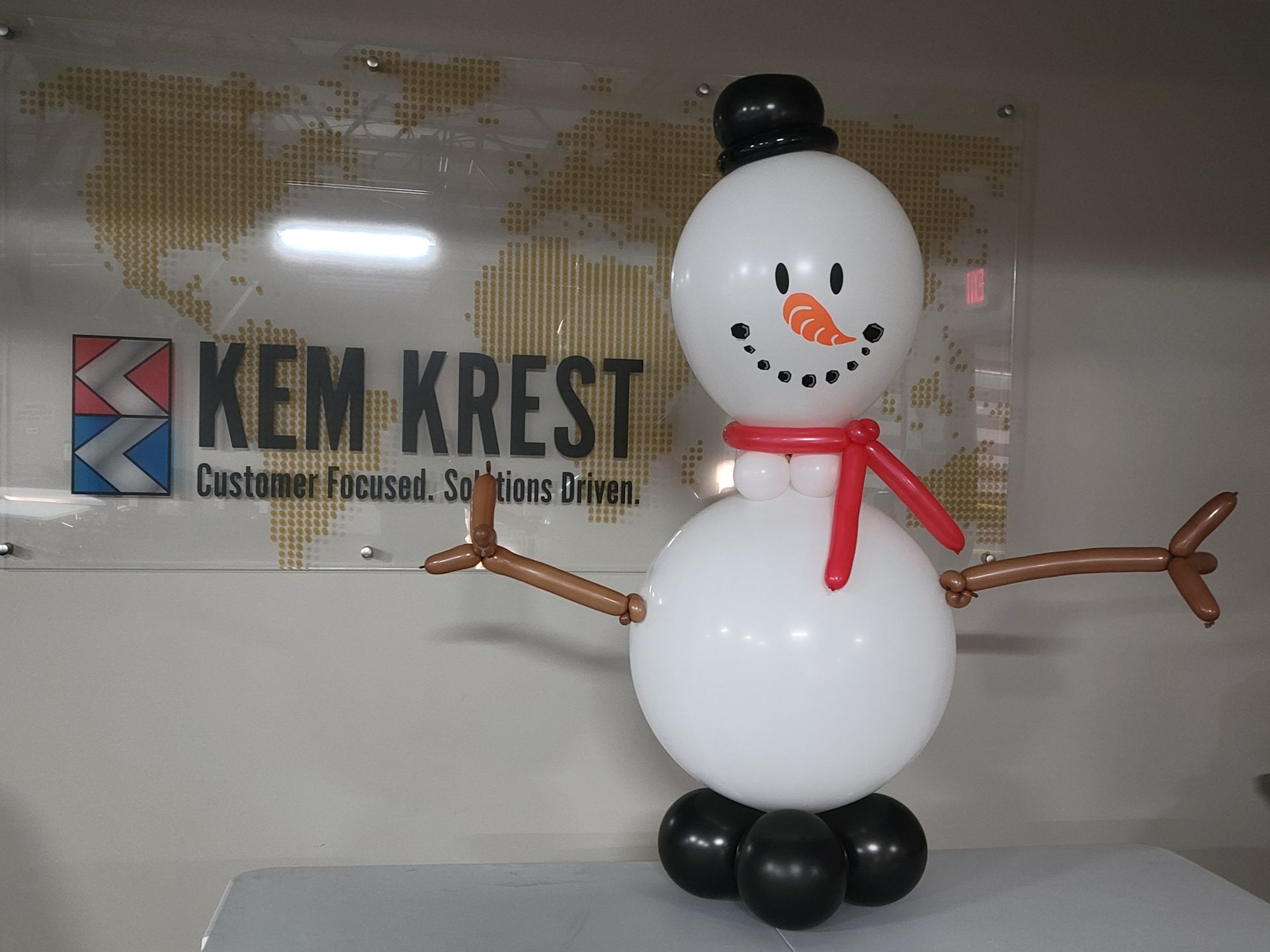 A snowman made out of balloons in front of a sign that says kem krest