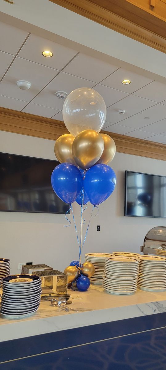 a bunch of blue and gold balloons are sitting on top of a table