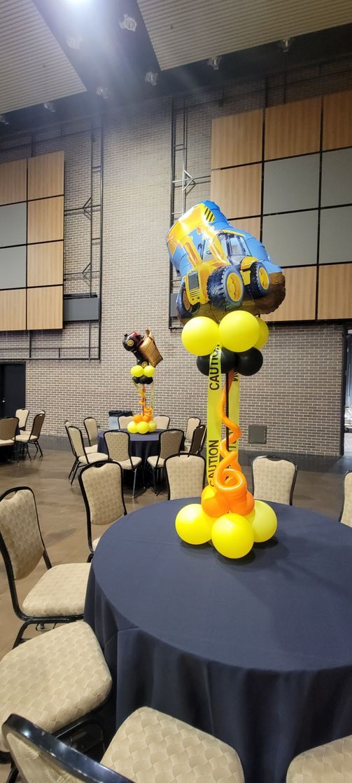 A table with a blue tablecloth and balloons on it.